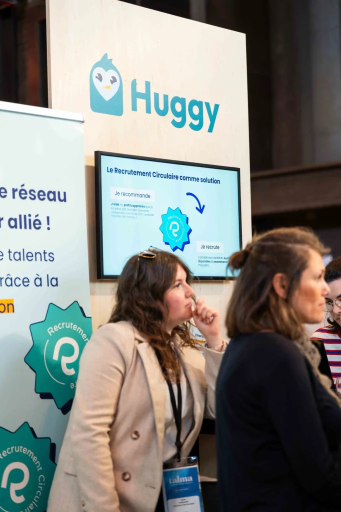 Deux membres de l’équipe Huggy sur un salon, devant le stand du Recrutement Circulaire